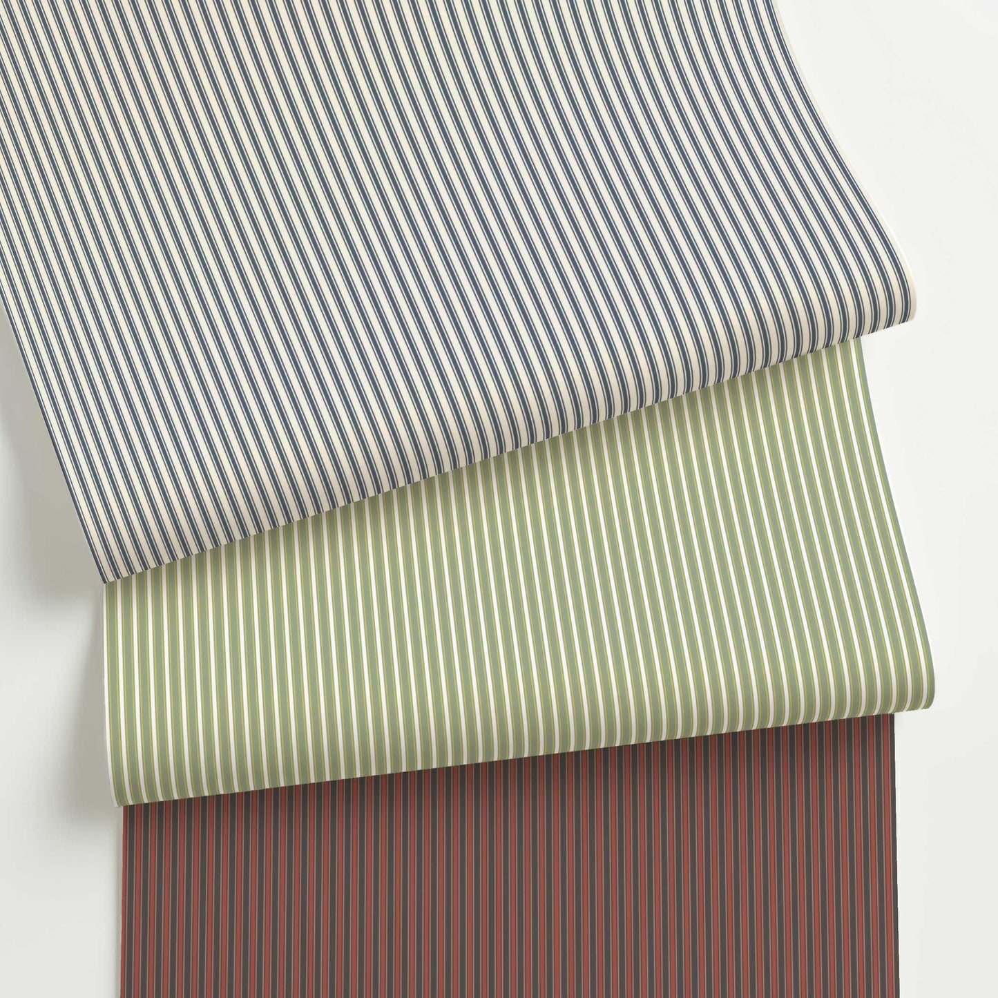 Three rolls of Meadowbrook custom French ticking stripe wallpaper in blue, green, and red colorways, showcasing the traditional fine-line pattern.