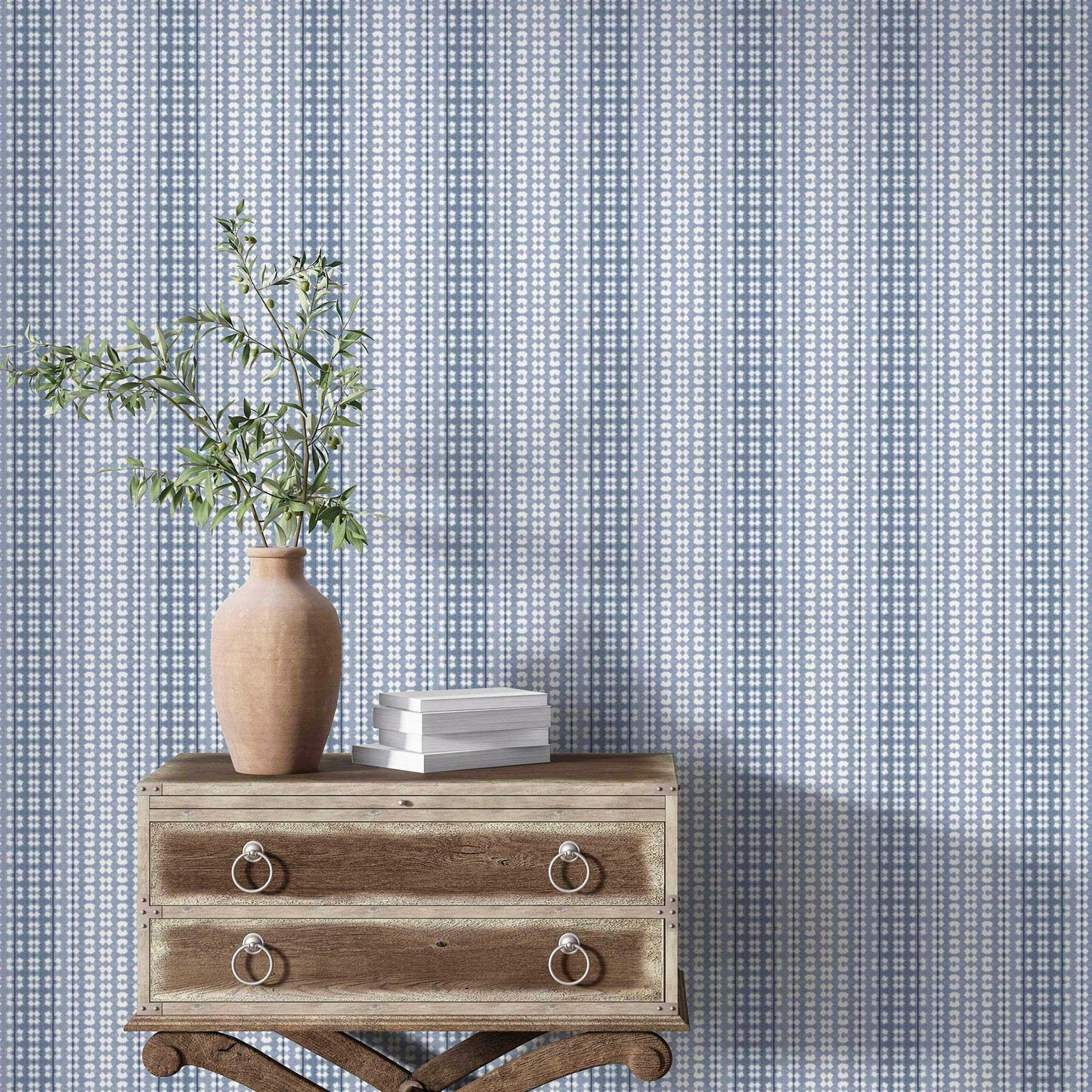 Dusty blue ombre striped wallpaper styled in an elegant room with a vintage wood dresser and pottery.