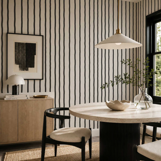 A modern dining room with black and white wavy striped wallpaper, round, white table, and chairs.