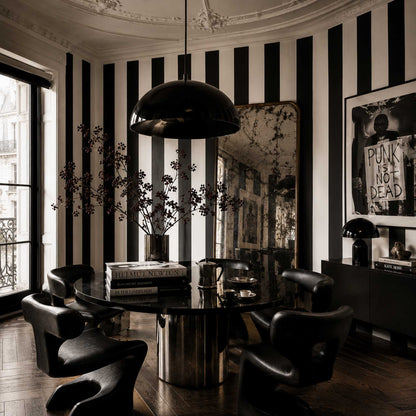 Modern interior in a traditional Parisian building with black and white striped walls, black round table, and stylish chairs.